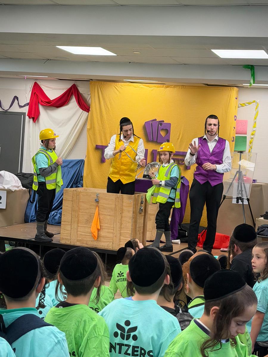 Mechy and Shloimy on stage with young volunteers in hard hats and safety vests